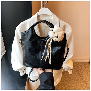 Close-up of black textured faux leather tote bag with a cute plush bear pendant accessory