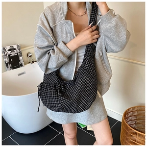 Detailed view of the black and white checkered fabric crossbody bag with side drawstring