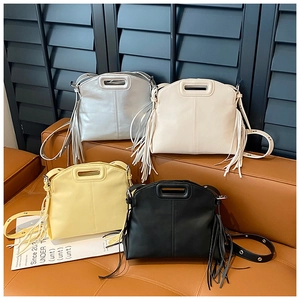 Detail view of large tote bags in silver, white, yellow and black with fringe accents