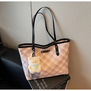 Sac cabas à carreaux rose et blanc avec peluche ours sur canapé en cuir