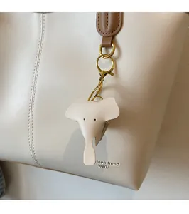 Detail of cream leather elephant bag charm with gold metal clasp on matching tote