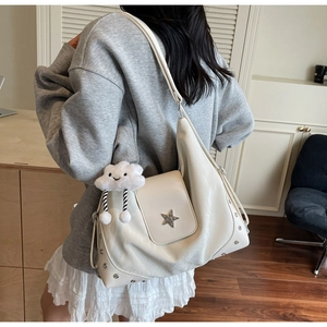 Vue détaillée du sac hobo blanc avec boucle étoile et breloque nuage en peluche sur le côté
