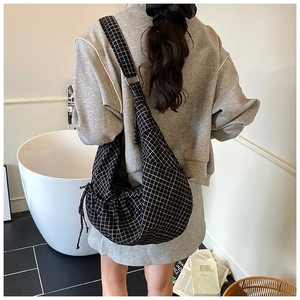 Detailed view of black and white checkered crossbody bag on a model's back