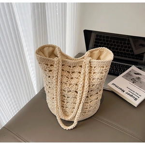 Detail of beige crochet straw bag with hollow pattern and inner lining on white desk