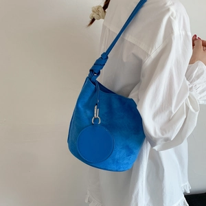 Detail of bright blue matte shoulder bucket bag with knot strap and circular pendant charm