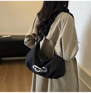 Détail de la bandoulière plissée noire sur un grand sac à main demi-lune