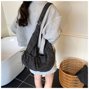 Close-up of black and white checkered crossbody bag with adjustable strap and side drawstrings