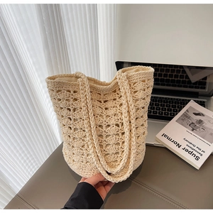 Close-up of beige crochet tote bag featuring shell-pattern knit and woven handles