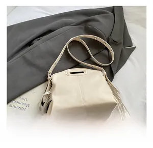 Detail of cream tote bag with long fringes, hollow handle and eyelet strap