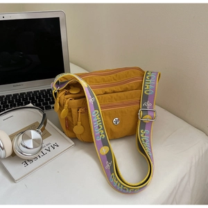 Detail view of bright yellow nylon crossbody bag with multi-zippered pockets and jacquard strap