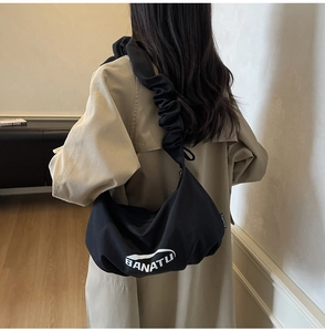 Détail du sac à main noir en toile avec bandoulière froncée et imprimé logo blanc