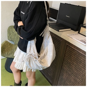 Detail view of large black and white windowpane check hobo bag with drawstring side