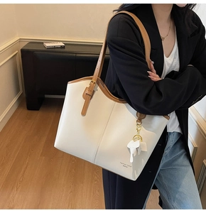 Detail shot of ivory leather tote bag with slim brown straps and elephant charm