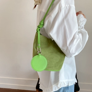 Green faux suede bucket bag shown on a model with a matching circular coin purse charm
