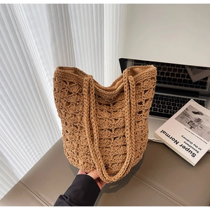 Close-up of brown crochet straw bucket bag with hollow diamond pattern and thick handle