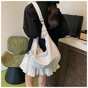 Detail of white grid pattern hobo bag with adjustable wide strap shown on model