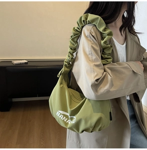 Détail du sac bandoulière plissé vert avocat avec imprimé BANANA porté par un mannequin