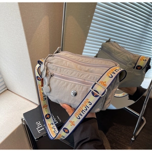 Detailed macro view showing the multi-zipper pockets and colorful embroidered strap of the bag