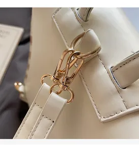 Close-up of premium gold-toned metal lobster clasp on a beige woven straw backpack strap