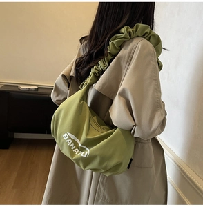 Détail du sac bandoulière vert avocat avec bandoulière froncée et imprimé logo