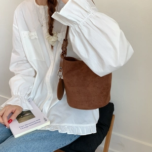 Brown frosted bucket bag detail with knotted shoulder strap and round hanging charm