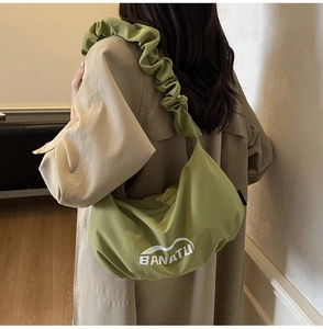 Détail de la bandoulière plissée verte du sac bandoulière décontracté avec logo blanc