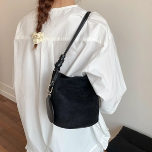 Detail view of black matte bucket bag with knotted leather strap and coin purse