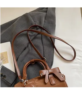 Detailed macro view of the brown cylinder bag with bow ornament and silver hardware