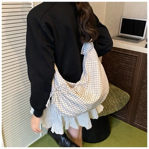 Macro view of black and white checkered tote bag with side drawstring details and soft fabric