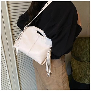 Detail of cream white tote bag featuring long leather tassels and soft textured material