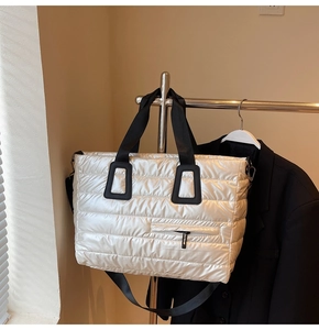 Vue détaillée d'un sac cabas argenté matelassé avec des poignées noires et une fermeture éclair