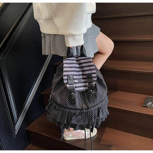 Detail eines schwarzen Rucksacks mit Punkten, Streifenklappe und Rüschendesign