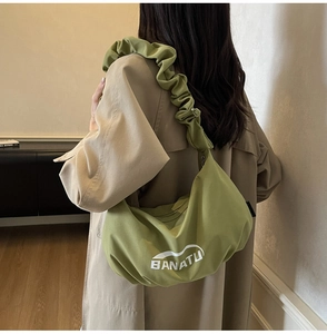 Vue détaillée du sac croissant vert matcha avec logo de marque et bandoulière à volants