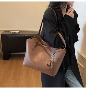 Minimalist brown leather tote bag with Fashion Trend logo carried on model shoulder