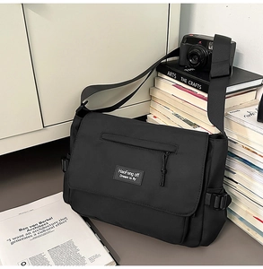 Detail of black crossbody messenger bag with adjustable side buckles and nylon texture