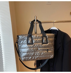 Détail du sac fourre-tout matelassé argenté avec poche zippée et doubles poignées noires