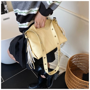 Detail view of the yellow tote bag with long side tassels and metallic eyelets on the strap