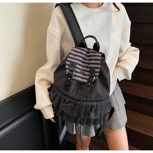 Detailansicht des schwarzen gepunkteten Rucksacks mit gestreifter Klappe und Rüschen