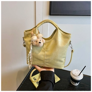 Detail shot of crocodile pattern PU leather tote bag with cute bear charm and silk ribbon