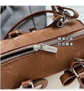 Detailed close-up of the smooth silver zipper and leather texture on a brown bowling bag