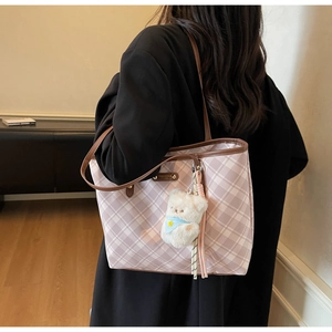 Détail du sac cabas à carreaux avec lanières en cuir et breloque ours sur mannequin