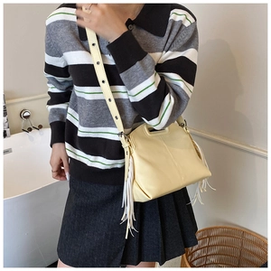 Detail view of cream yellow tote bag with side fringe and adjustable shoulder strap