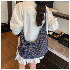 Detail of navy blue checkered hobo bag with drawstring closure and large capacity