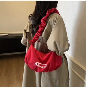 Gros plan du sac banane en toile rouge avec bandoulière plissée et logo blanc