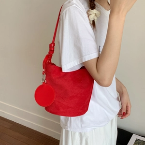 Detail of red suede bucket bag with matching round coin purse and adjustable knotted strap