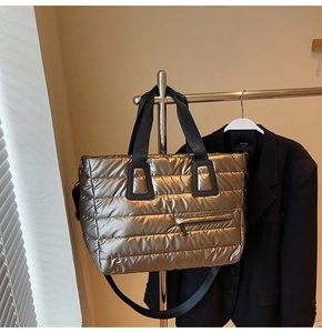 Détail du sac fourre-tout matelassé doré avec coutures transversales et poche zippée