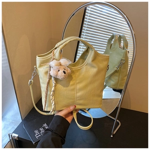 Close-up of light green crocodile pattern tote bag with a cute plush bear pendant
