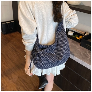 Detailed side view of navy checkered crescent bag with drawstring and adjustable strap