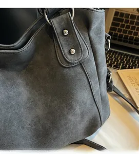 Détail du cabas en daim gris foncé avec boucle à anneau métallique argenté et rivets