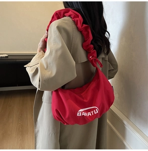 Détail du sac en toile rouge en forme de croissant avec volants plissés et logo